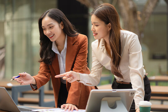 Two female coder or developer working overtime using a computer display in problem solving.