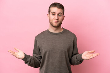 Young caucasian man isolated on pink background having doubts