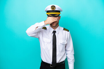 Airplane caucasian pilot isolated on blue background covering eyes by hands. Do not want to see something © luismolinero
