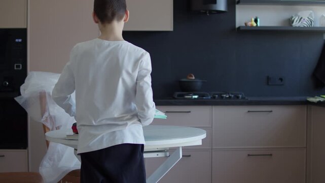 Schoolboy preparing school supplies at kitchen table at home