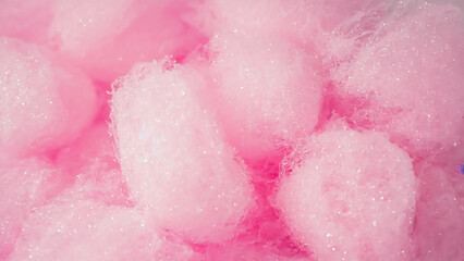 Fototapeta premium Close-up of fluffy pink cotton candy with sparkling sugar crystals, creating a sweet and whimsical texture background.