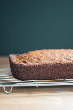 Section of fresh homemade banana bread cooling on rack with dark background