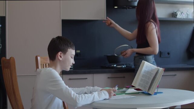 Schoolboy fooling around while doing homework at kitchen table