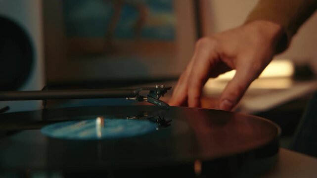 Man in Dimly Lit Room Placing Vinyl Record onto Turntable for Music