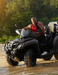 Naklejka premium A man engages in extreme ATV riding on sand beach early in the morning