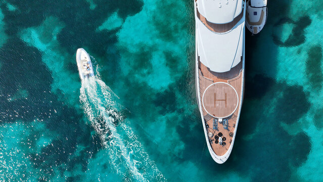 Aerial drone top down photo of amazing luxury yacht nose with wooden deck and helipad anchored in tropical exotic paradise bay with crystal clear turquoise sea