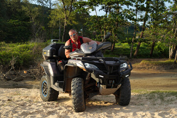 Naklejka premium A man engages in extreme ATV riding on sand beach early in the morning