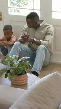 Vertical video: Leaning father in shirt calming by door, child in pink shirt meeting gaze