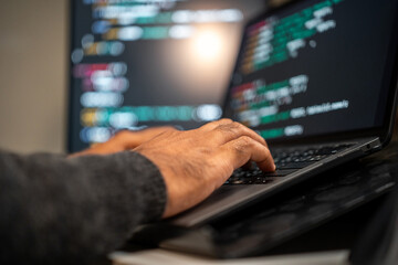 Male programmer wearing glasses works late at night with green code reflecting on his lenses focusing on software development coding and cybersecurity analysis.