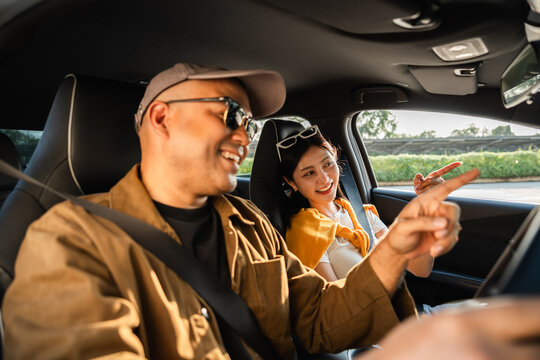 Young asian couple man and woman travel by car on a bright day beautiful blue sky sunlight. They was happy along the way trip. safety driving car vacation. Travel tourism vehicle.
