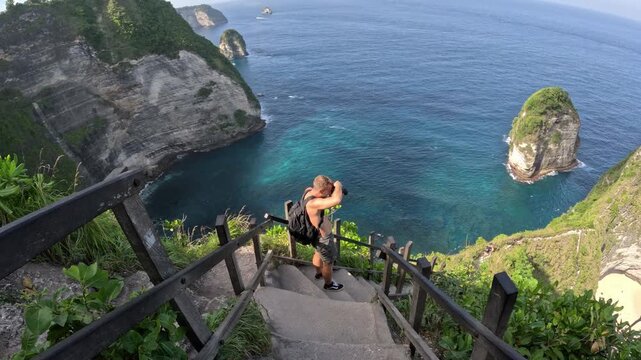 Tourist photographer taking pictures at kelingking beach bali