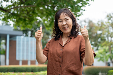 Fototapeta premium Portrait of smiling pretty senior asian woman 60 years old with urban natural park background, happy retirement lady with healthy aging in life security protection insurance for future planning.