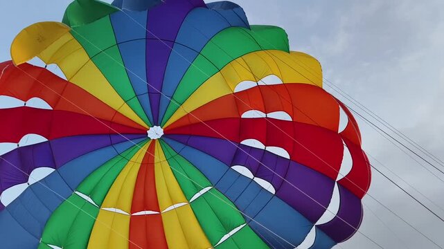 Bright rainbow parasail canopy filling sky over ocean 