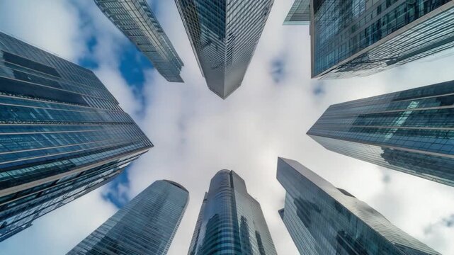 A low angle shot of skyscrapers reaching for the cloudy sky with blue and white clouds