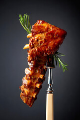 Grilled pork ribs with rosemary on a fork.