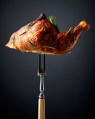 Smoked chicken thigh on a fork sprinkled with rosemary.