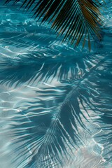 Fototapeta premium Palm tree shadows on blue water background, palm branch on beach pattern, ocean wave sunlight palm shadow