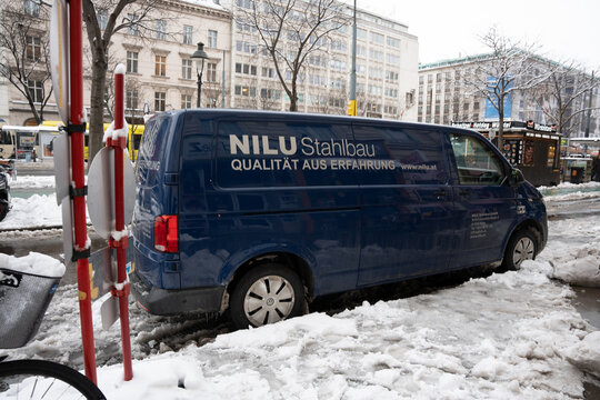 Vienna, Austria- Feb 21, 2026: A blue van with the logo of NILU Stahlbau parked in a snow-covered street, surrounded by urban architecture and winter landscape.