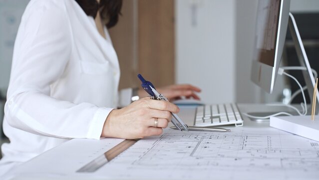 Architect working on building blueprint plans, designing new projects with computer and drawing tools. Business and architecture concept
