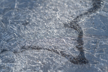Naklejka premium Spring ice reveals dark channels. Subtle sparkle shows thawing ice movement. Dark channels etched across pale ice sheets capture subtle sparkle and natural thawing motion