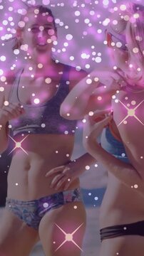 Vertical video: Sparkle overlay moving, two women dancing and adjusting bikinis, promoting swimwear