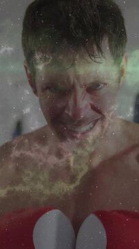 Vertical video: Boxer tightening jaw and thrusting heart gloves toward camera, training with nebula