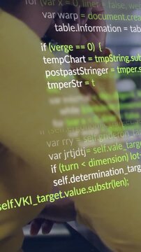 Vertical video: Coder leaning on desk watching screen, screen showing code scrolling across face