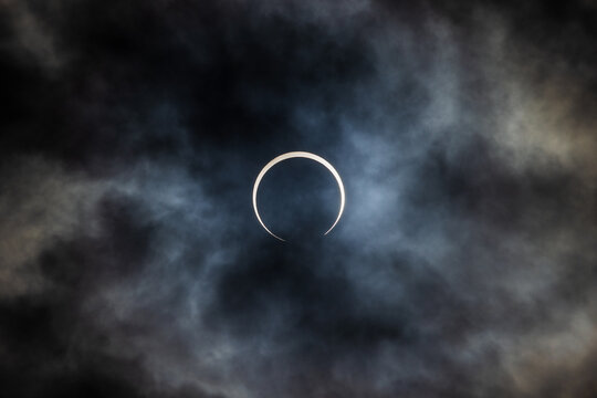 Annular solar eclipse in partial phase with the sun covered in clouds