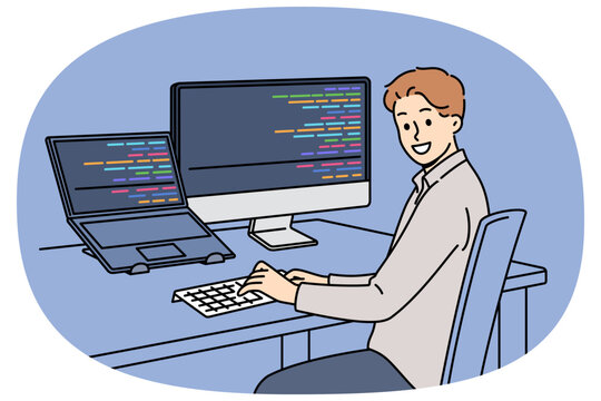 Man programmer types code and looks at camera, sitting at table with computer and laptop. Successful guy programmer develops software or application, working in team with UI or UX designers