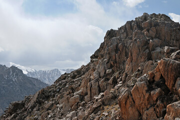 Fototapeta premium Sharp granite mountain peak with snow covered ridges of Tian Shan range in the background