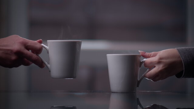 woman and man drink hot tea together in the evening, close-up of glasses with hot tea, have fun and enjoy