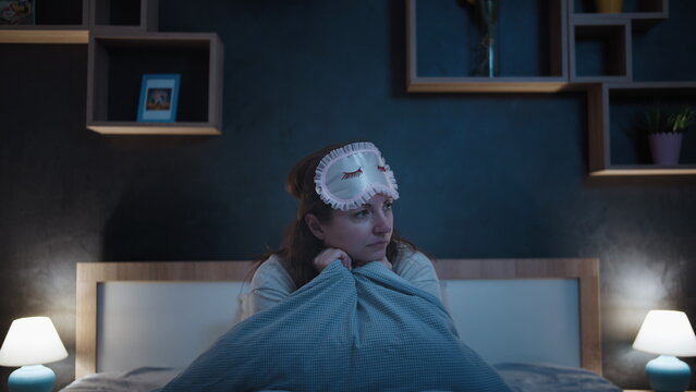 Insomniac Woman Sitting in Bed at Night Wearing Sleep Mask, have fun and enjoy