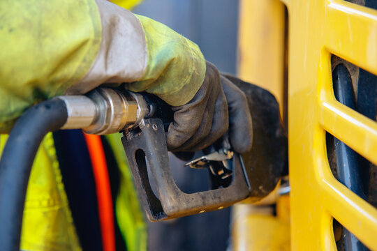 Worker fuels machinery at construction site during daylight hours