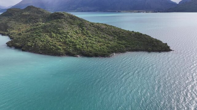 flying around Pigeon Island, located  in the middle of Lake Wakatipu, near Glenorchy in South Island region of Otago, New Zealand, surrounded by mountain landscape - 4k aerial video footage