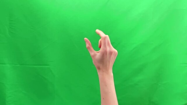 Two fingers performing pinch zoom gesture on green chroma background. Human hand enlarging digital image through touch screen interaction. Mobile interface navigation concept for scale control.