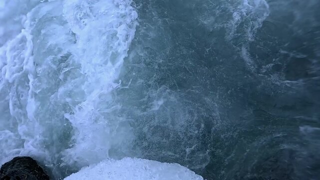 Winter storm in the Black Sea, waves wash over coastal rocks, splashes of foaming saline water at the shoreline