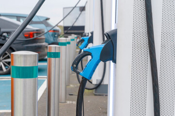 Electric vehicle charging station in a public area with multiple charging points and cars nearby © Iryna