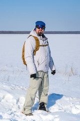 Bearded man with backpack standing alone in snowy winter landscape, enjoying solitude and personal freedom