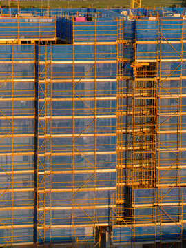 Aerial view of screening and scaffolding on the side of a highrise building under construction