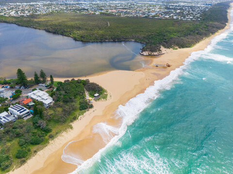 Aerial view of patterns on a sandy beach in front of an inland lake behind a sand bar