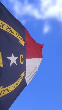 North Carolina State Flag Waving Against Bright Blue Sky Background