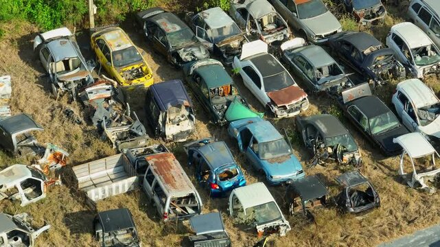 Aerial drone close-up view of a crowded car scrapyard filled with damaged and rusting vehicles, illustrating automotive salvage, old car disposal, and the recycling of dismantled automobile parts.
