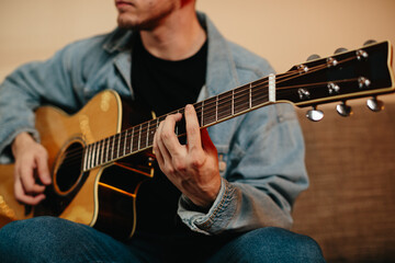 Young musician composing music playing acoustic guitar at home