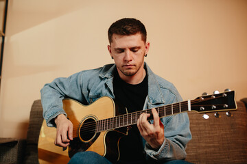 Obraz premium Young musician composing music playing acoustic guitar at home