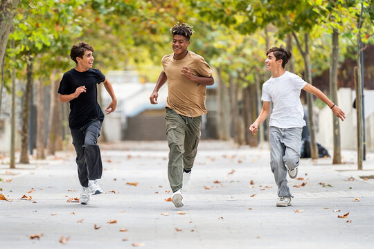 Teenage friends laugh and run together outdoors