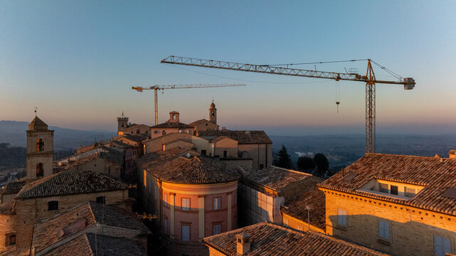 Sunrise view of historic Cingoli with construction cranes