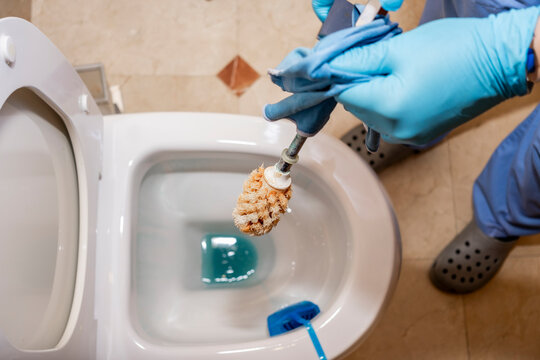 Woman cleaning a bathroom with gloves and brush