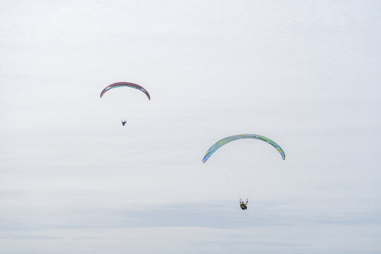 Paragliders soaring above Cordoama in cloudy skies