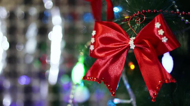 A Christmas tree decorated with a bow on a background of bright lights from a garland. 4k video