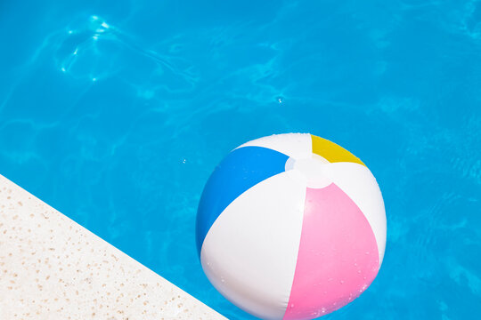Colorful beach ball floating in a clear blue pool
